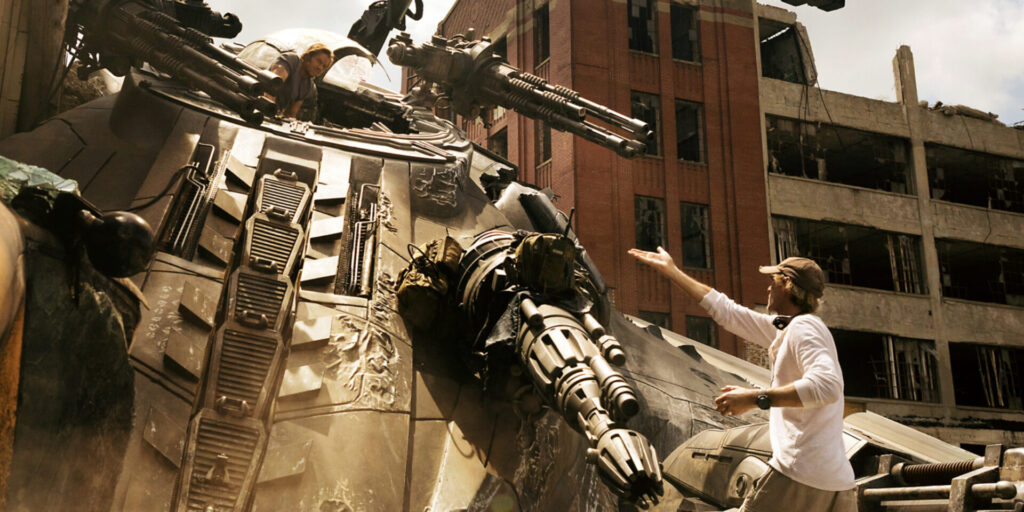 Photo of movie set with mark Wahlberg inside a giant transformer , Michael Bay the director is looking up and gesturing , presumably giving some direction to the actor inside the giant machine on the movie set which Steph calls the Transformers debacle. 